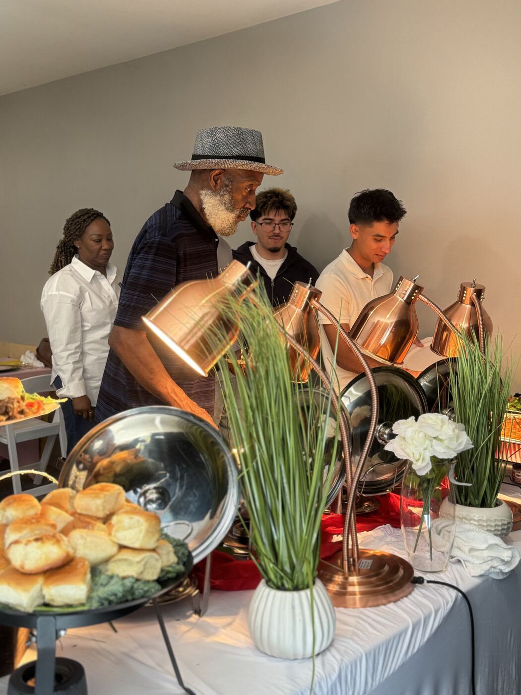 Guests serving themselves at a catered buffet with copper heat lamps